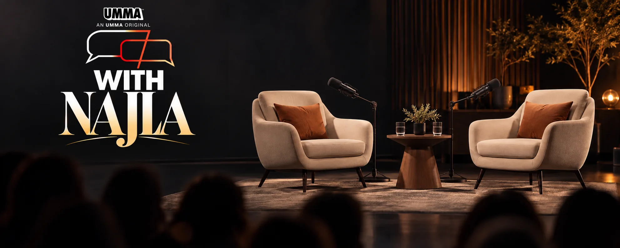 The With Najla set: two armchairs facing each other under studio microphones on a lit stage, with the show's logo on the wall behind and an audience seated in the dark.